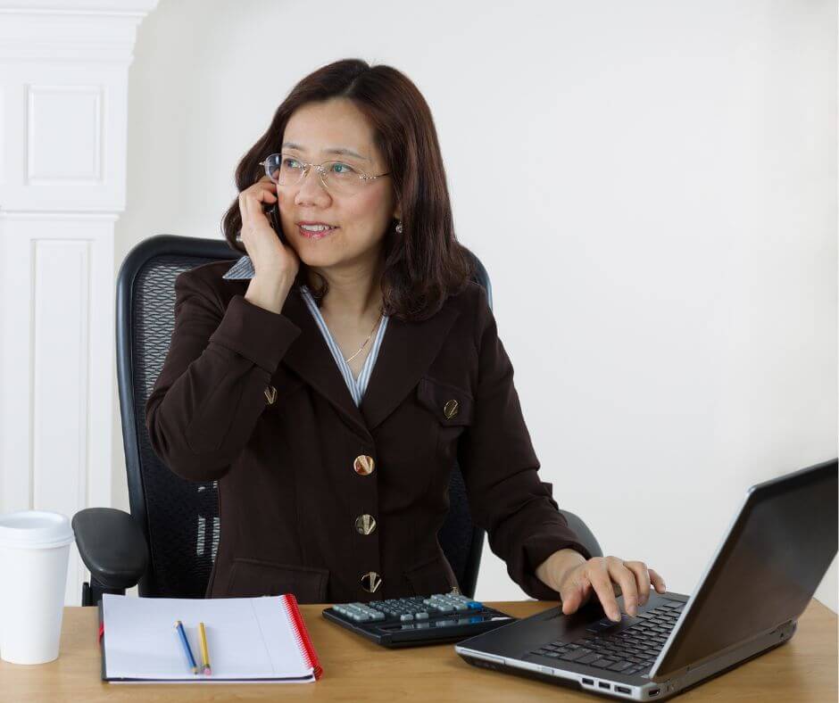 A woman communicating with the irs on the phone while sitting at a desk.